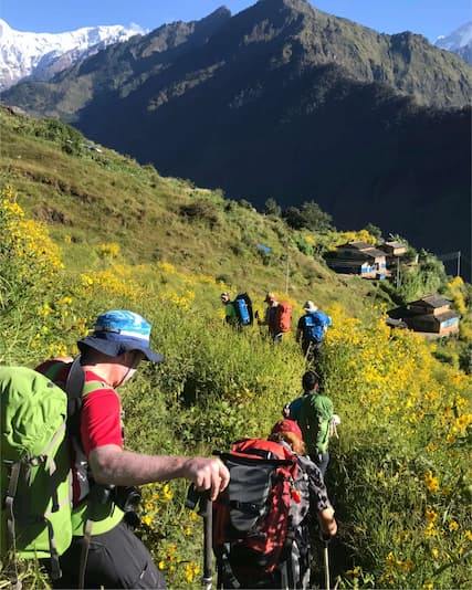 Trekkers walking along a scenic trail in the Nepal Himalayas surrounded by mountains and valleys